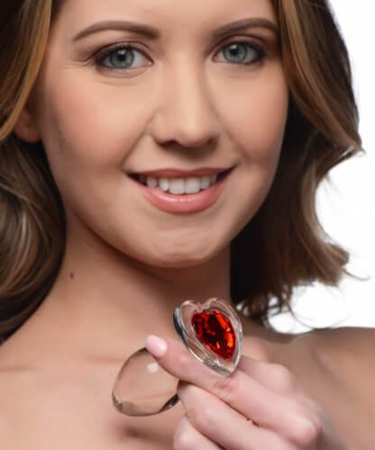 Woman holding Booty Sparks Red Heart Glass Anal Plug by XR Brands with a sparkling red heart gem.