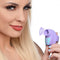 Woman smiling while holding Inmi Shegasm Mini 12X Clit Stimulator in Purple, showcasing its compact and ergonomic design.