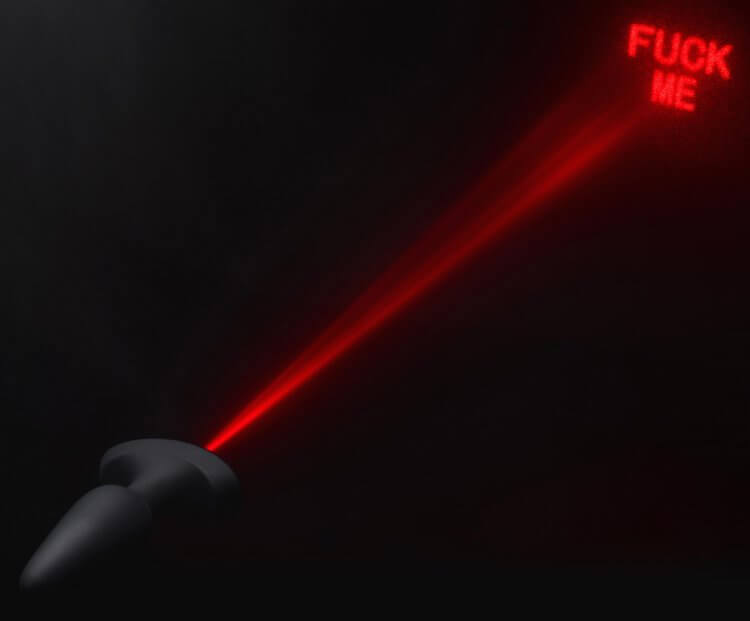 "Booty Sparks anal plug projecting red laser light 'Fuck Me' in dark background"