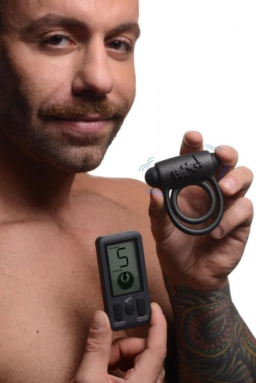 A shirtless man holds the Bang! Platinum Series Cock Ring with Remote Control and its remote, showcasing its features.