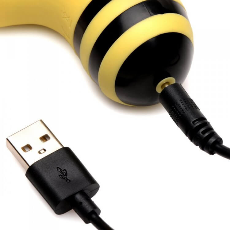 Close-up of the Shegasm Sucky Bee Clit Stimulator charging with a USB cable, highlighting its compact design.