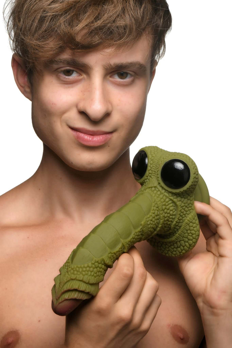 Man holding the Creature Cocks Swamp Monster Silicone Dildo with scaly ridges and glassy eyes.