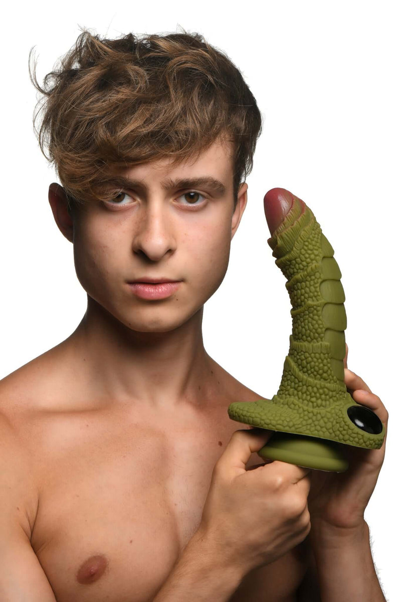 Man holding the green Swamp Monster Silicone Dildo with scaly ridges and realistic texture.