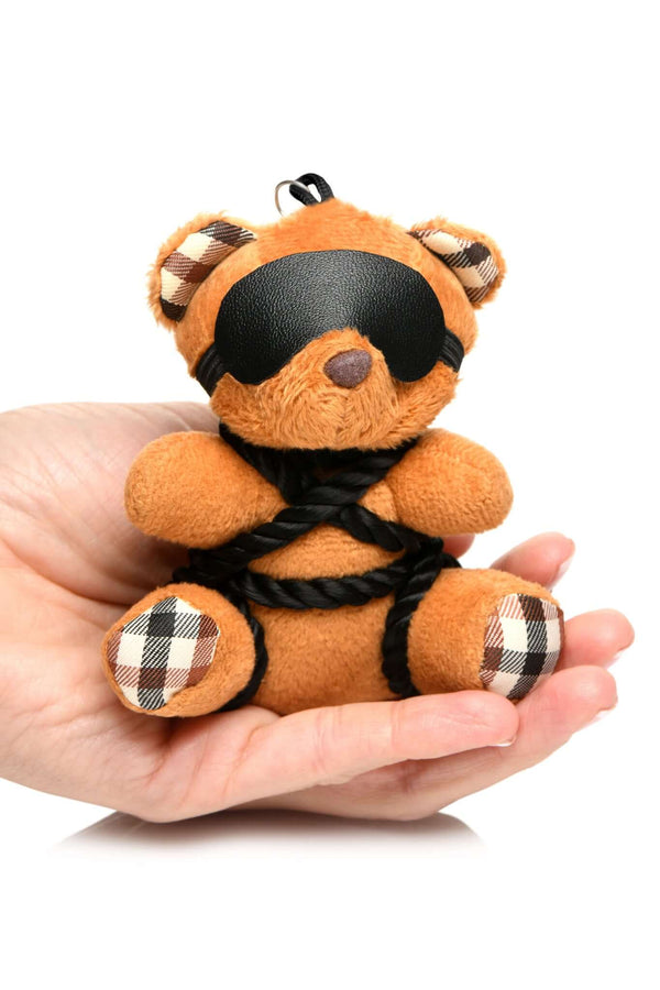 Kinky bondage bear keychain with blindfold and rope, held in hand, perfect for playful desk, backpack, or key accessory.