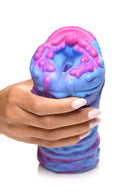 Close-up of a hand holding the vibrant, extraterrestrial-designed Creature Cocks Cyclone Squishy Alien Vagina Stroker by XR Brands.