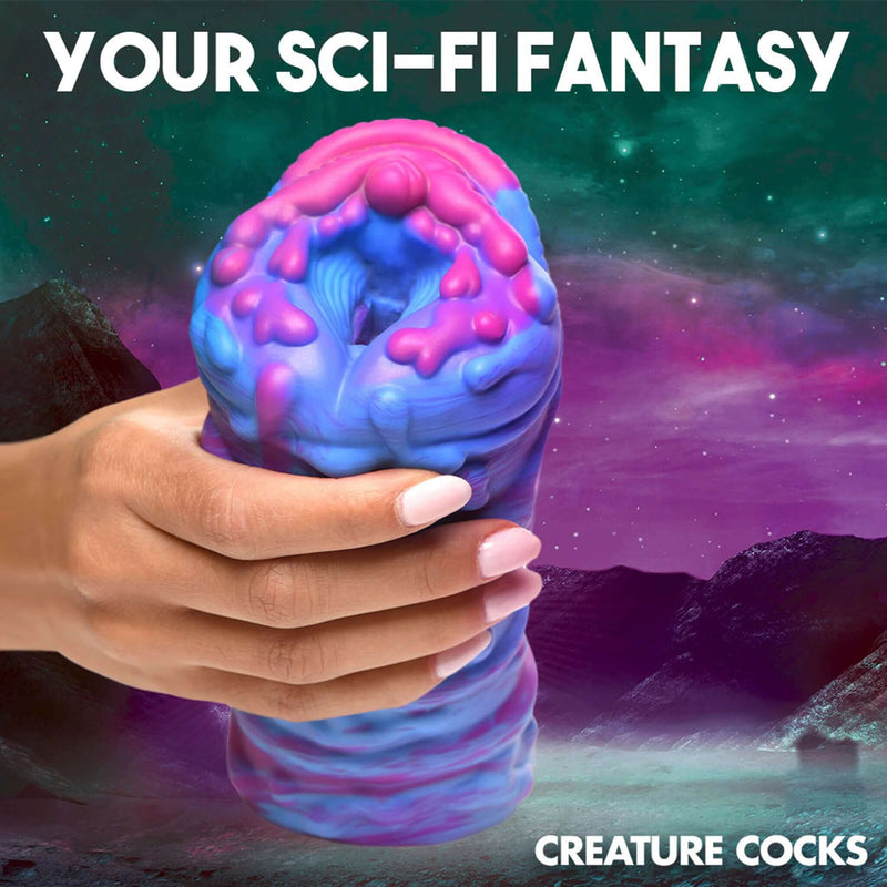 Hand holding Creature Cocks Cyclone Squishy Alien Vagina Stroker with vibrant colors against a sci-fi background.
