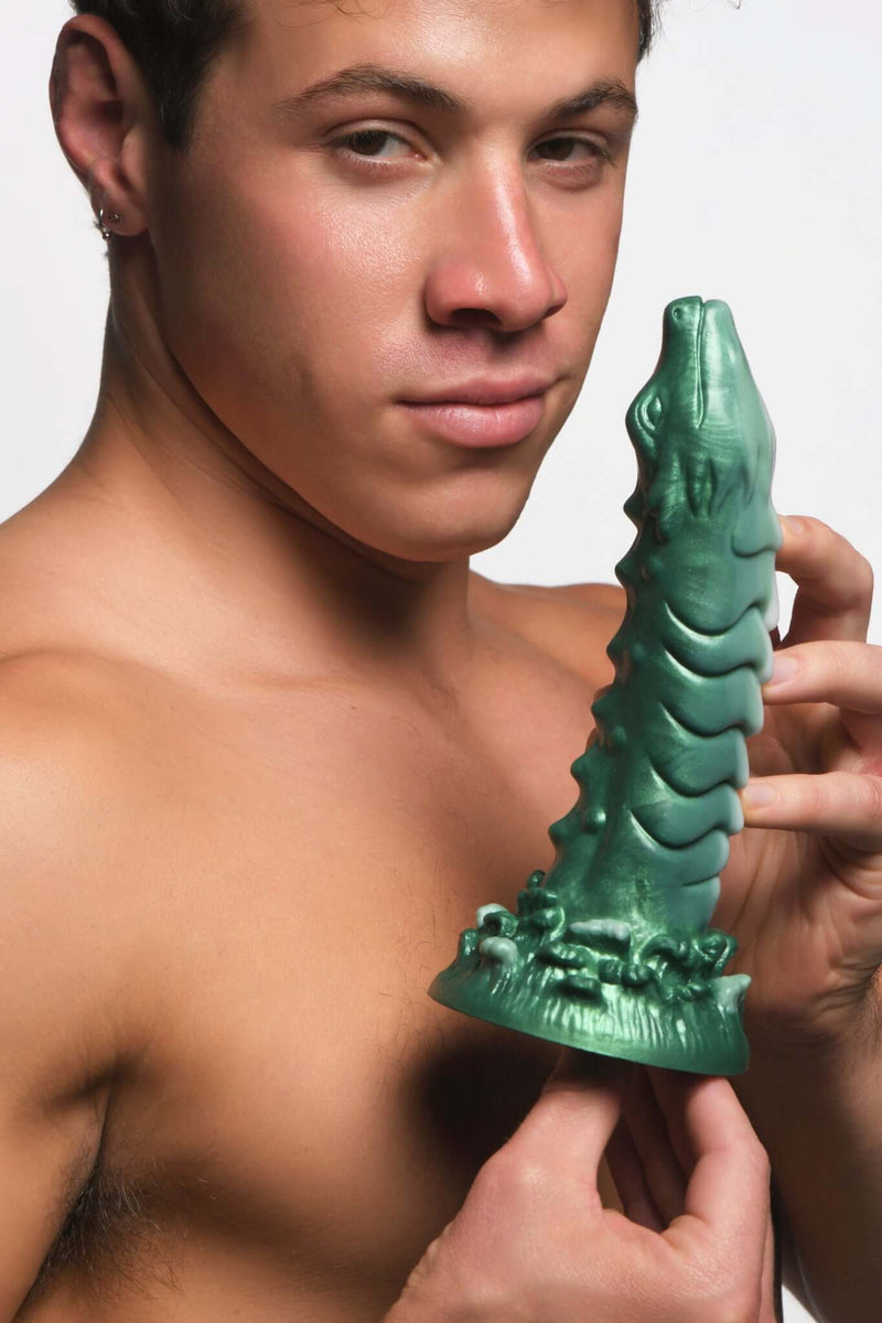 Man holding the green, dragon-inspired Creature Cock silicone dildo for G-Spot or P-Spot stimulation by XR Brands