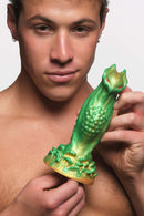 Man holding Creature Cocks Nebula Alien green and gold silicone dildo by XR Brands with red eyes.