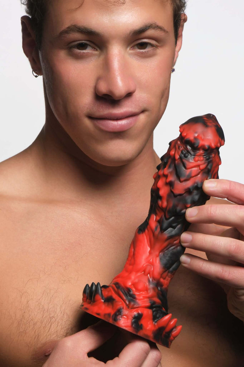Man holding Creature Cocks Reaper Silicone Dildo in red and black with textured surface and spikes.