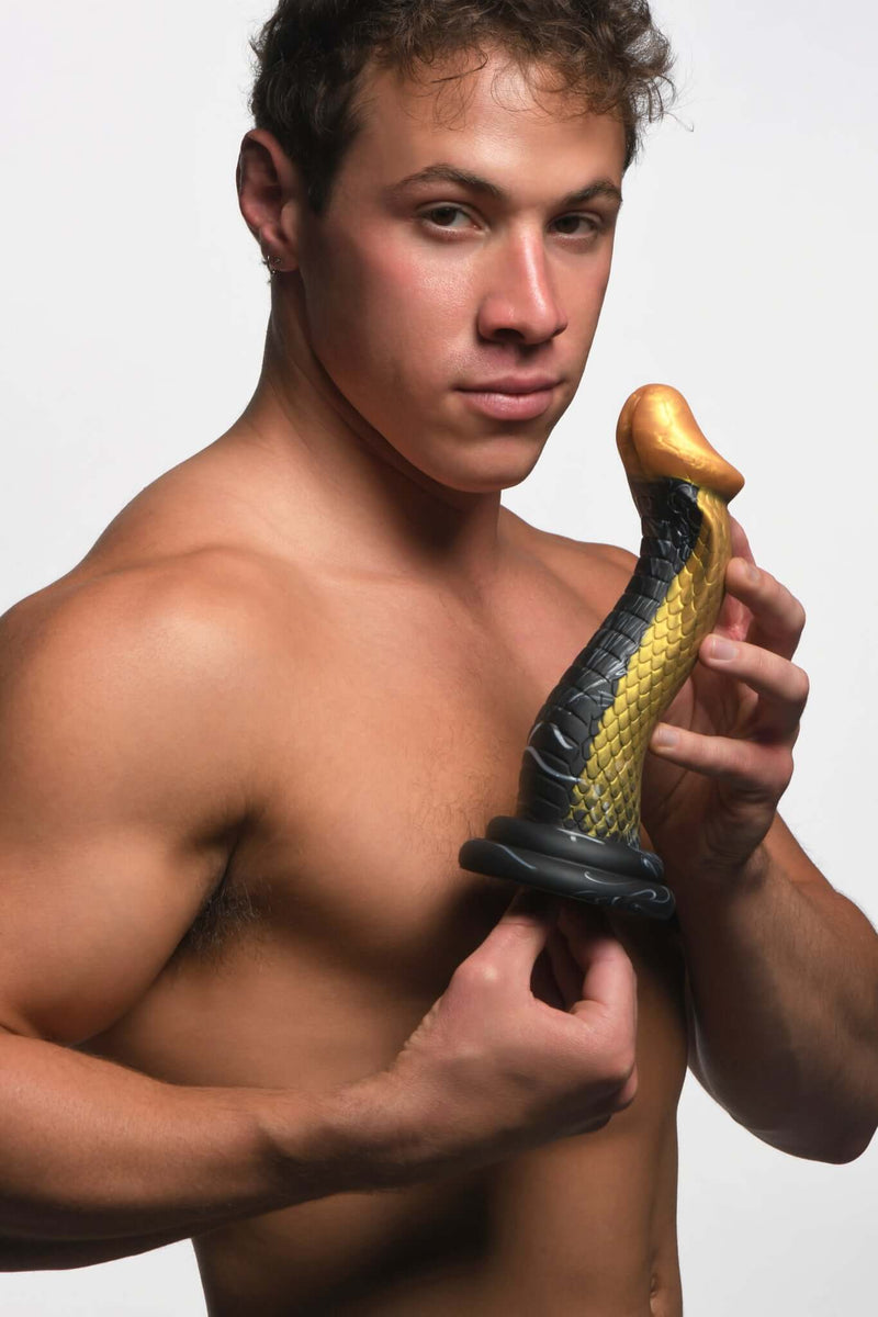 Shirtless man holding Creature Cocks Golden Mamba royal silicone dildo by XR Brands with gold and black S-Curve design.