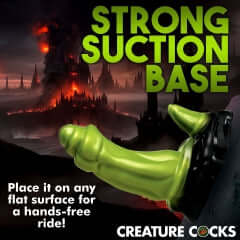 Creature Cocks Orc Silicone Dildo with strong suction base against fantasy background for hands-free play.